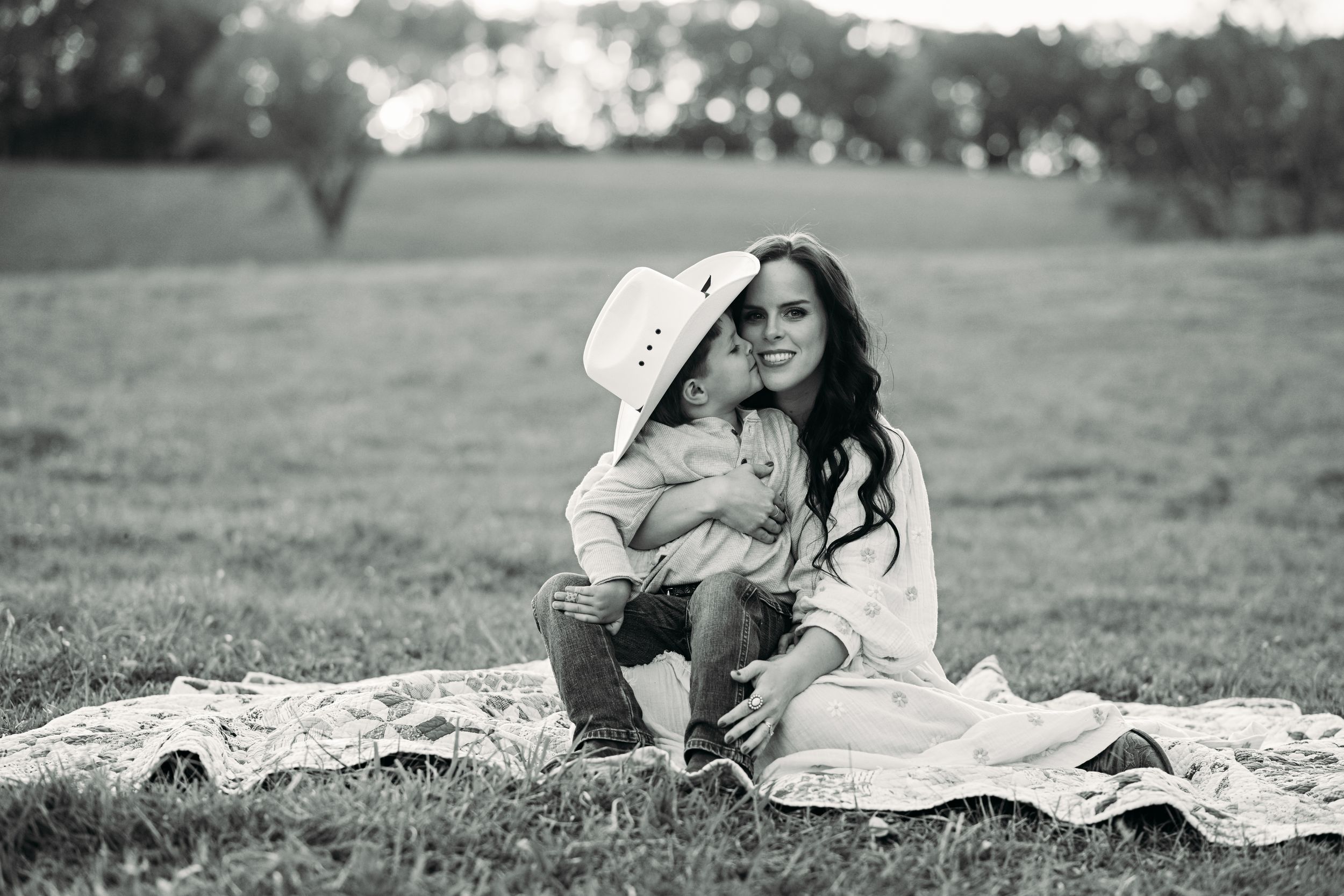 A tender black and white portrait captured on a blanket in a field.