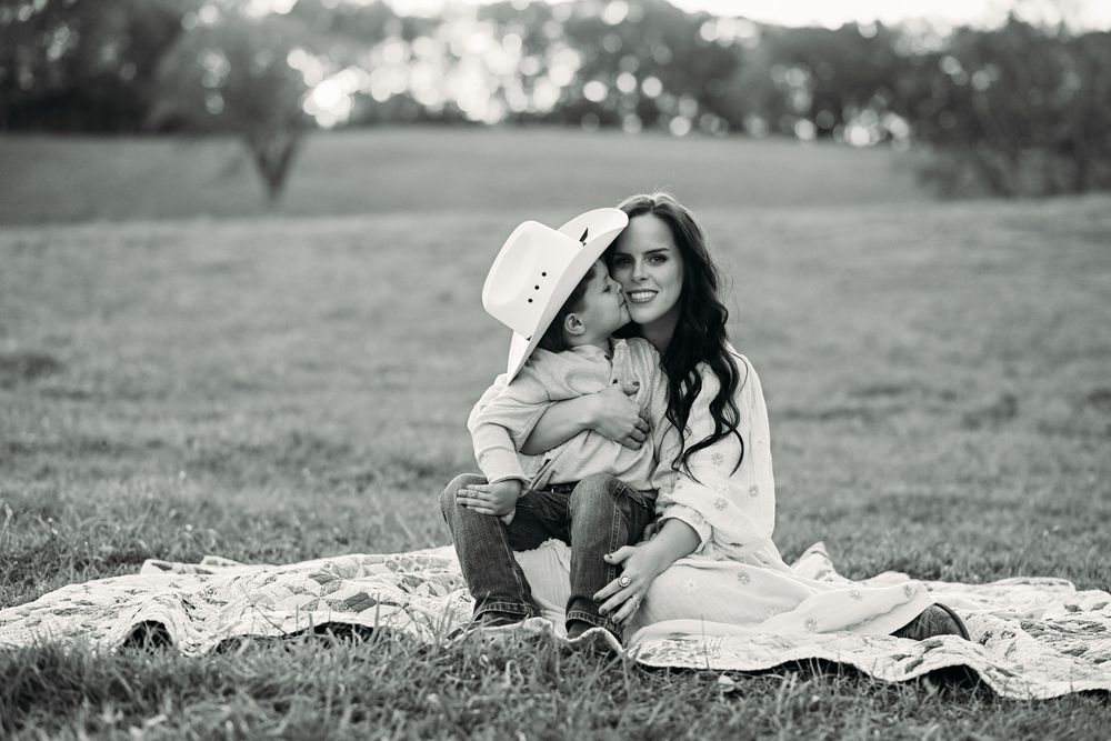 A tender black and white portrait captured on a blanket in a field.