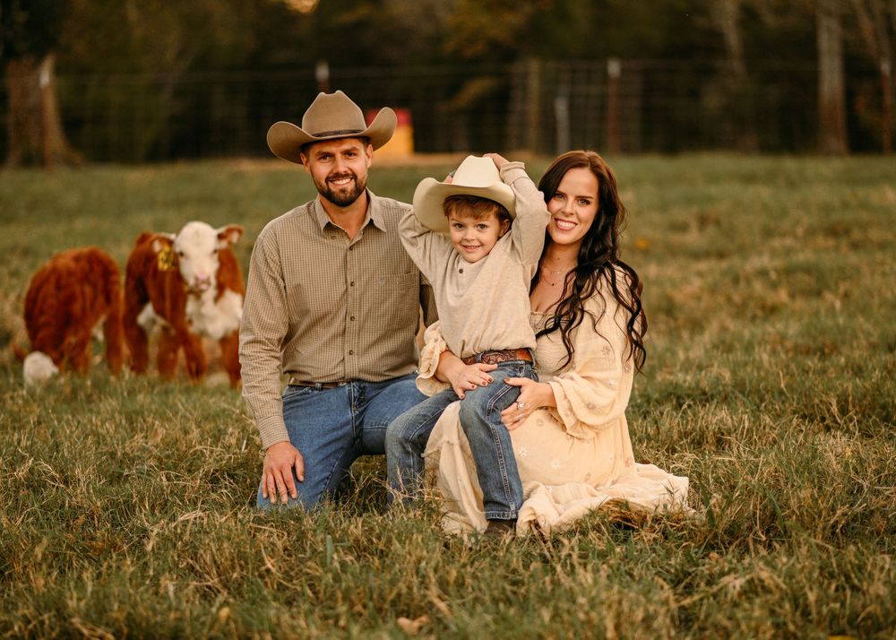 A countryside family portrait with cattle grazing in the background during golden hour.