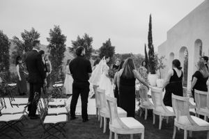 Bride in lace gown walking down the aisle on cliffside overlooking ocean at luxury wedding venue Jeune Perché