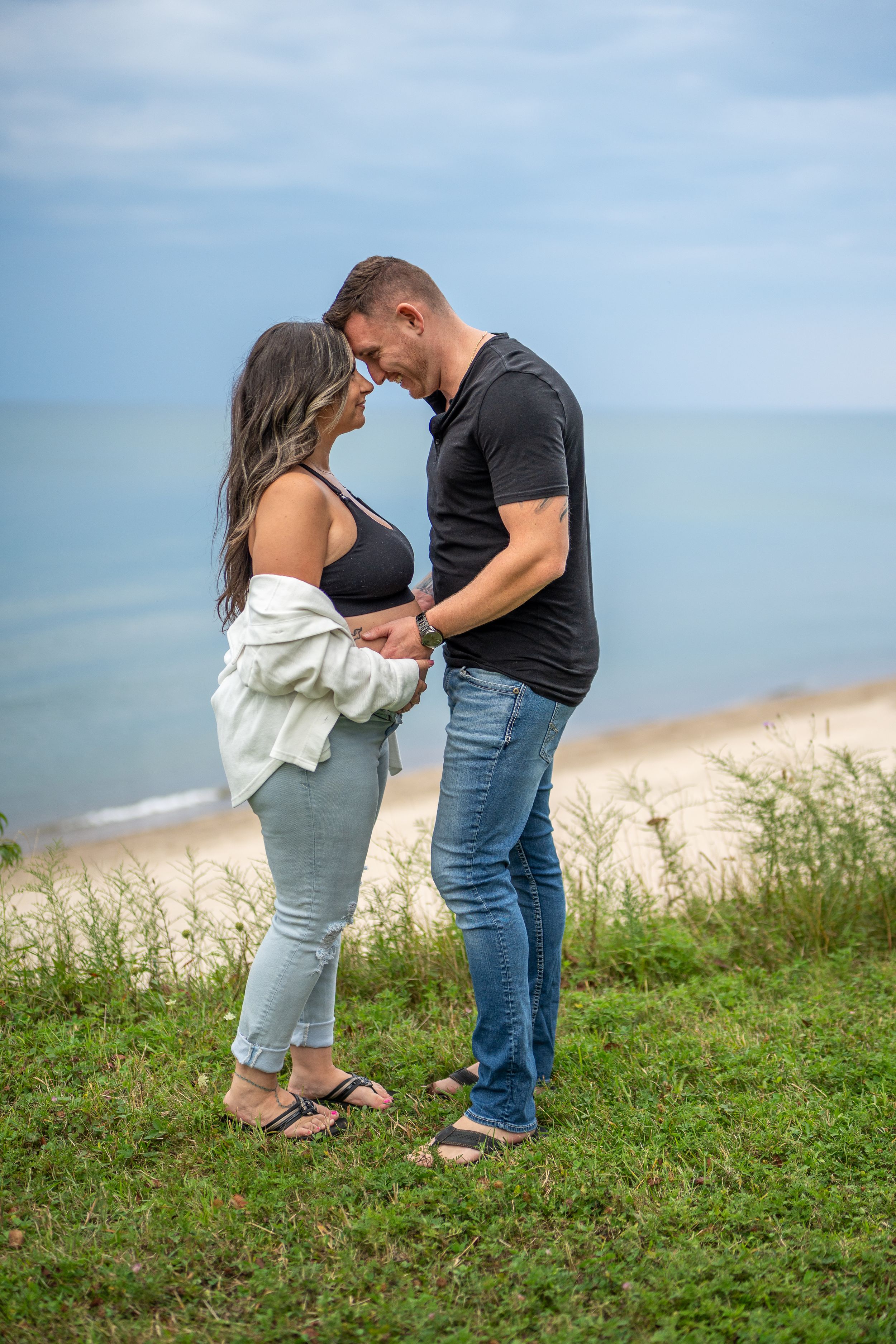 A romantic couple embracing on a clifftop overlooking the ocean.