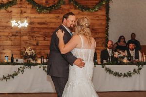 A romantic first dance at a rustic wedding reception with wooden walls and greenery decor.