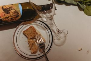A partially eaten dessert plate with a wine glass and bottle in the background.