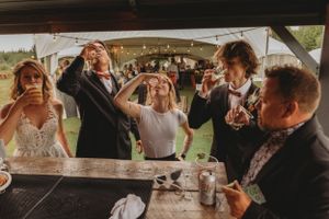 Wedding party taking celebratory shots at an outdoor bar.