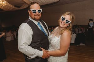 A fun wedding reception moment with the couple wearing matching sunglasses on the dance floor.