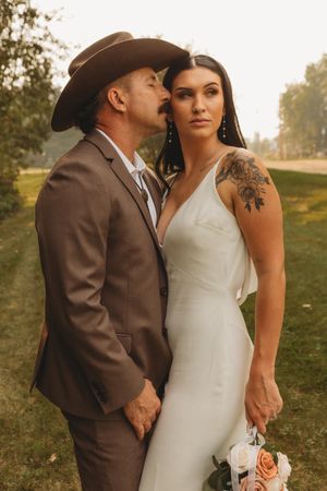 Couple in wedding attire embraces during golden hour photo session outdoors.