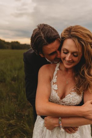 An intimate embrace in a grassy field during golden hour.