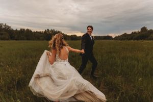 A playful moment between the couple in a rustic field at sunset.