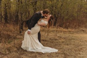 Dramatic wedding pose in a rustic field with flowing lace dress.