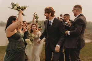 Wedding party celebrates with bouquets and laughter in an outdoor ceremony.