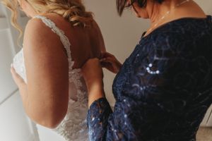 Close-up of dress fitting adjustments being made to white wedding gown.