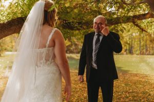 A touching first look moment at a fall wedding captured in golden outdoor lighting.