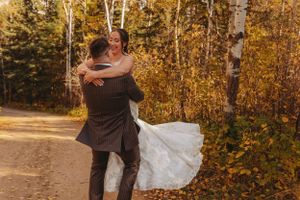 A celebratory embrace captured on a forest path during an autumn wedding.