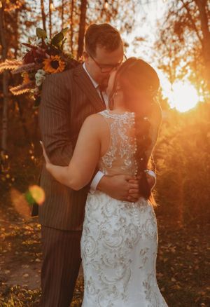A romantic embrace during golden hour with autumn foliage and sunlight in the background.