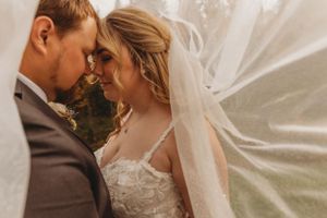 Intimate moment between newlyweds as bride's veil flows in the autumn breeze.