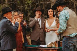 Wedding ceremony taking place at a rustic outdoor venue surrounded by autumn foliage.