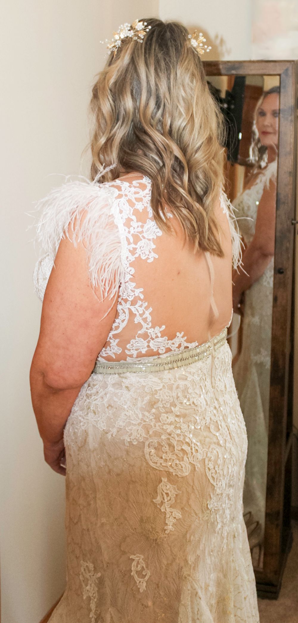 A detailed view of an ornate cream lace wedding dress back with delicate floral patterns and sheer mesh details.