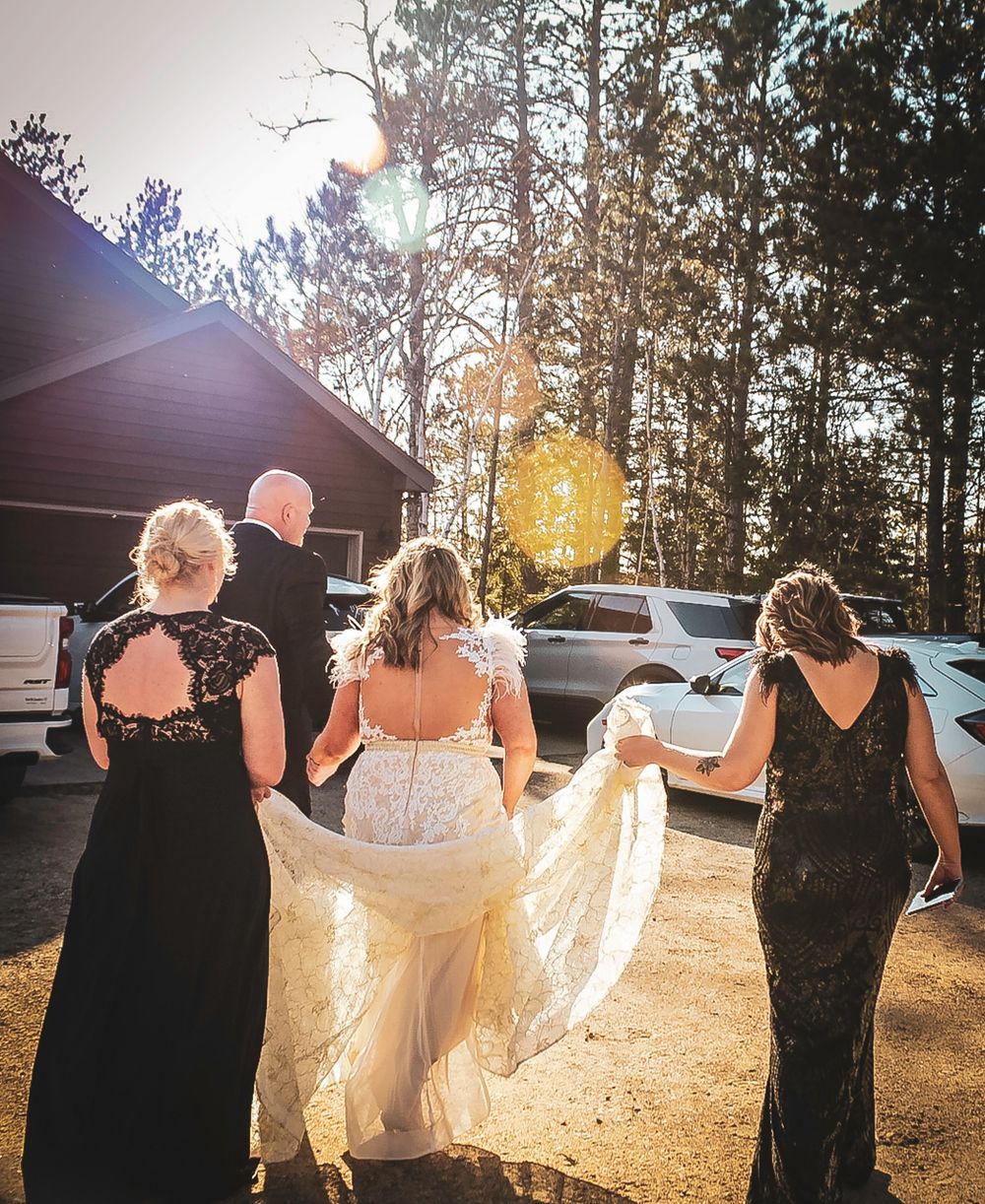 Wedding party walking together on a sunlit path near a rustic cabin in the woods during golden hour.