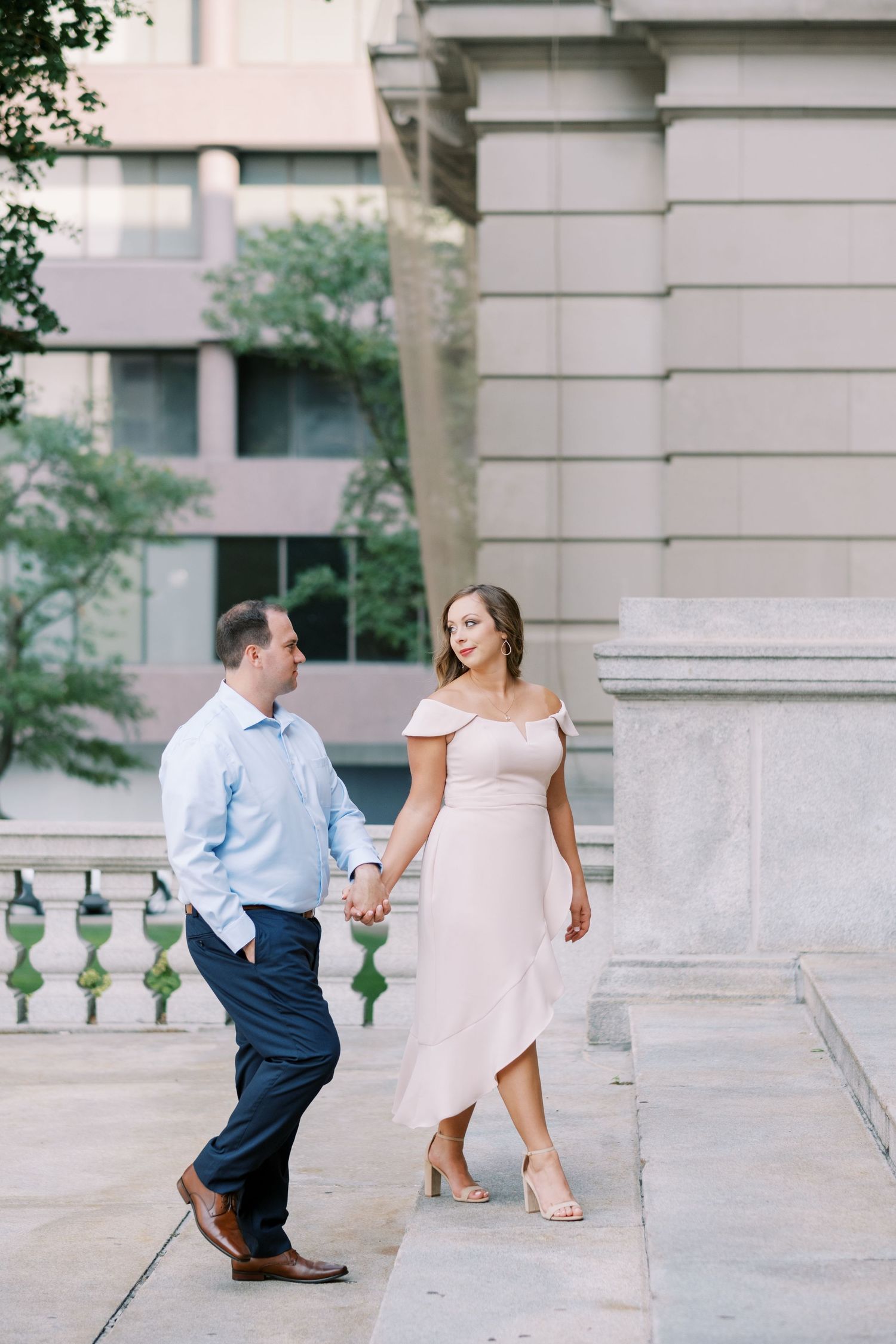 Couple playfully walking and dancing on stone steps outside a building.