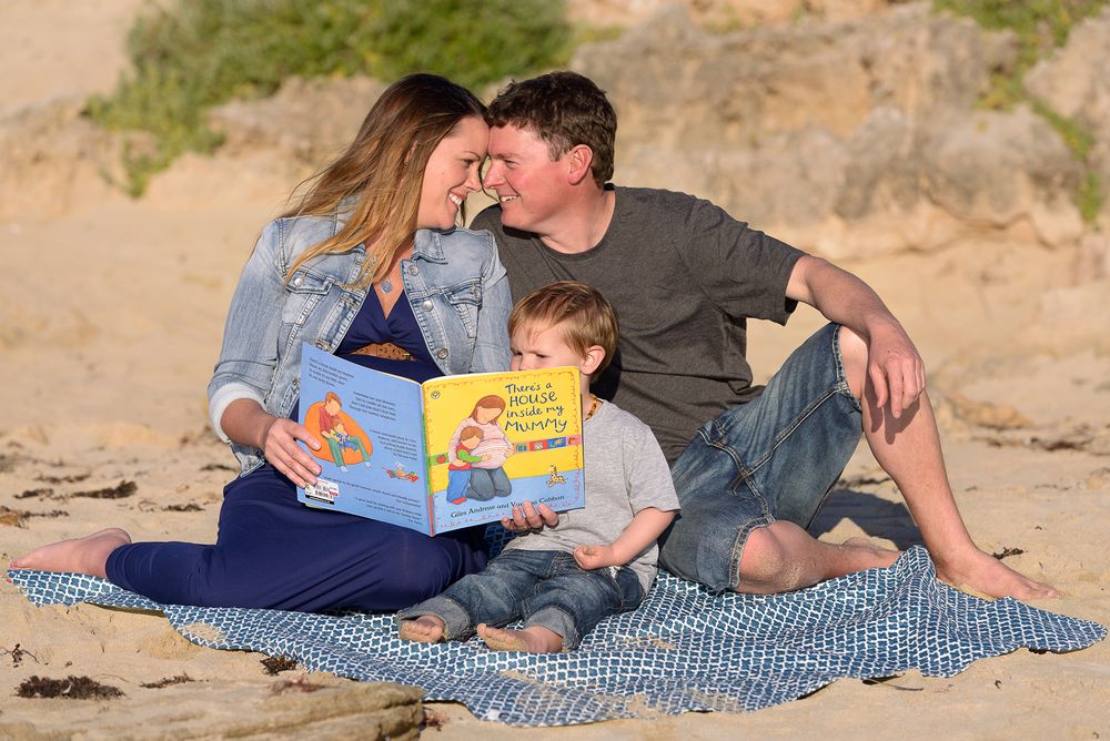 Young family on beach reading book - Kelly Chapman Photographer Perth