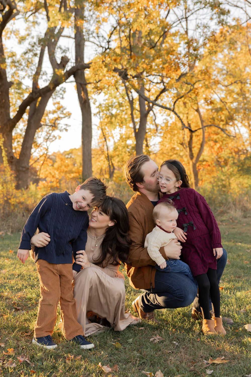 playful family moments together on a grassy hill during golden hour in fall time in Rochester Hills Michigan bear creek park