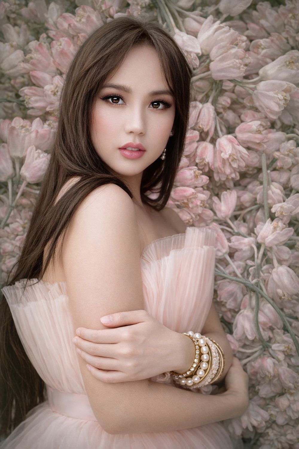 Artistic portrait against pink floral backdrop with soft lighting and delicate ruffled dress details.
