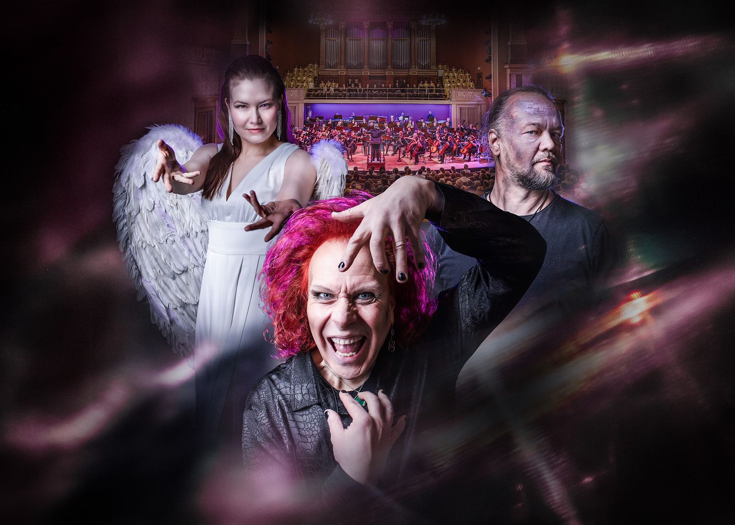 Three theatrical performers pose dramatically with angel wings, pink hair, and intense expressions against an orchestra backdrop.