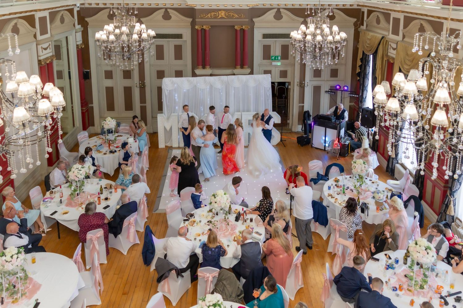 Elegant wedding reception in a grand ballroom with chandeliers, guests seated at decorated tables at The Grand Hotel, Hartlepool.