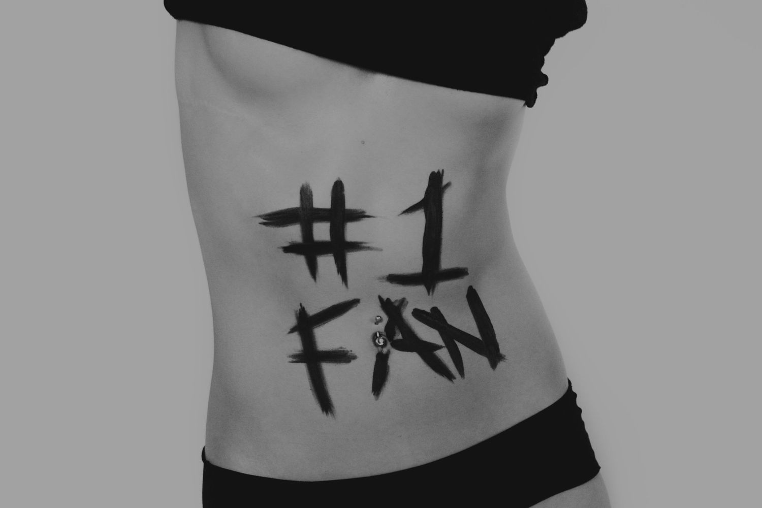 Black and white photo of a torso with #1 FAN written in bold brush strokes on the side.