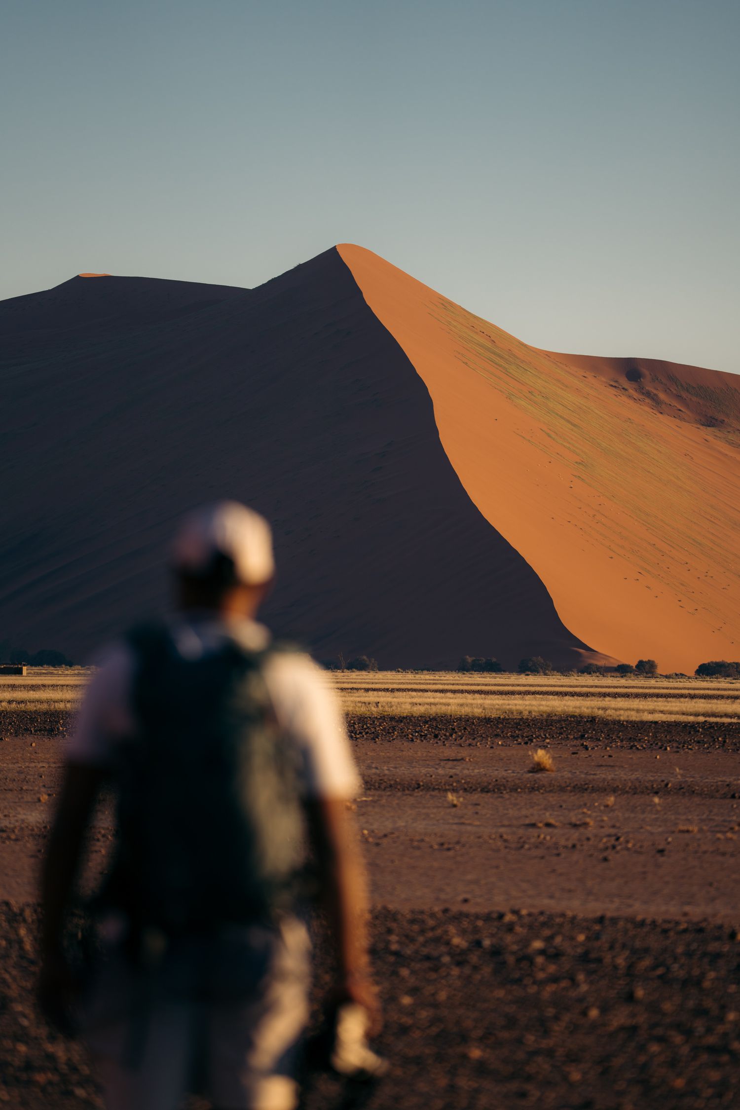 homme qui marche vers une dune orange du désert en namibie