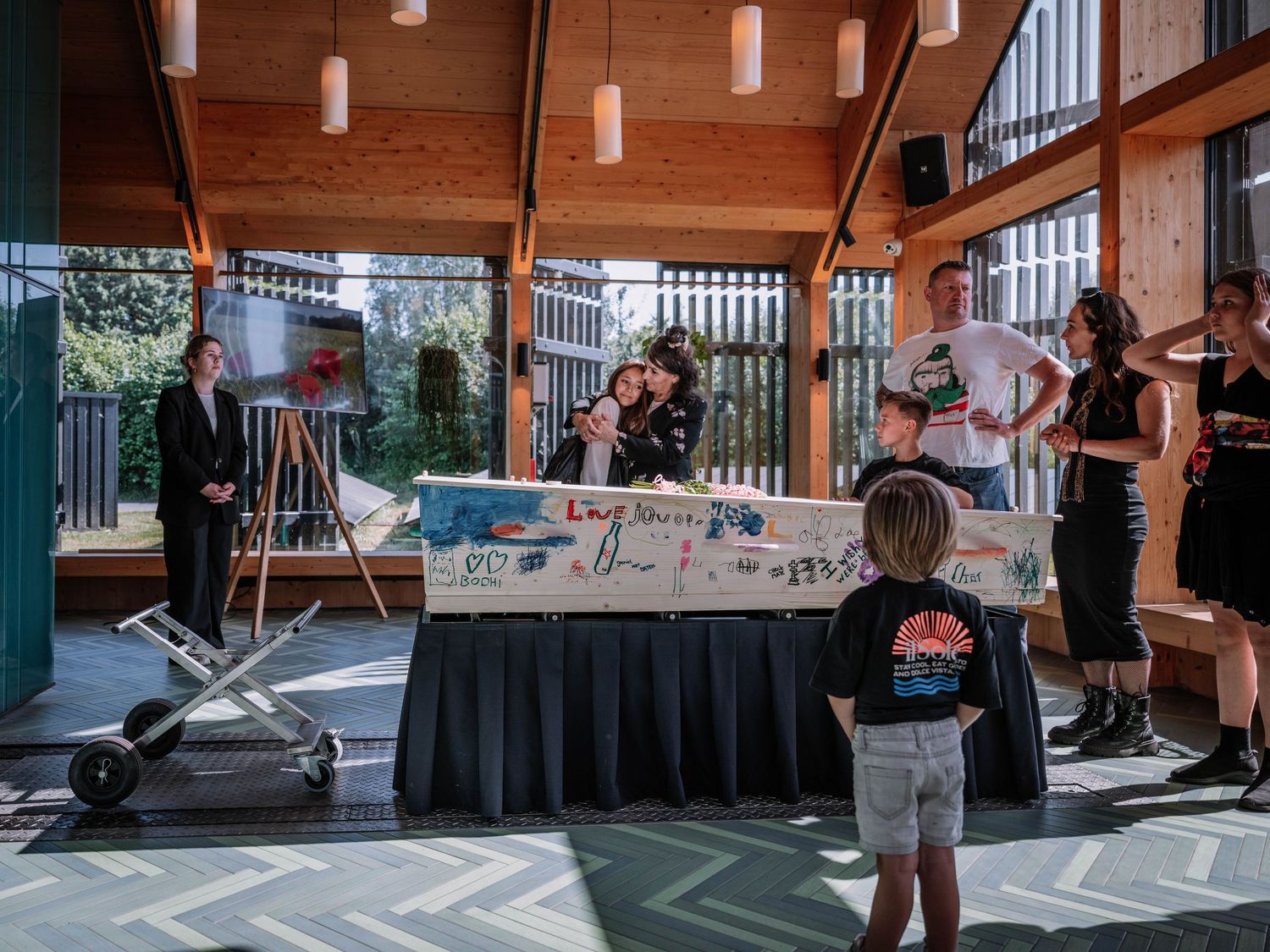 People gathered around a decorated table at an indoor event venue with wooden architecture and natural lighting.