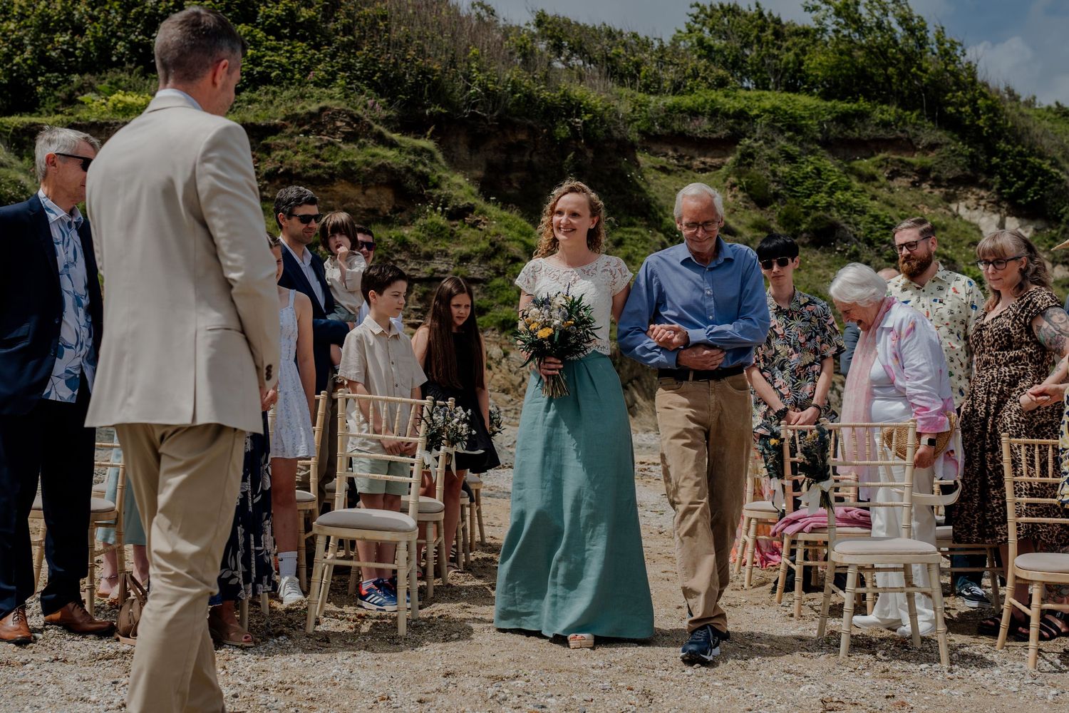 Bride walking on the beach towards groom during outside ceremony wedding at hotel Meudon