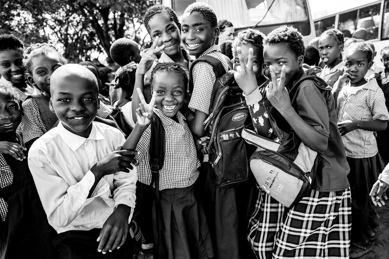 Black and white photo of African children sitting together, with a young child in a jacket looking directly at the camera.