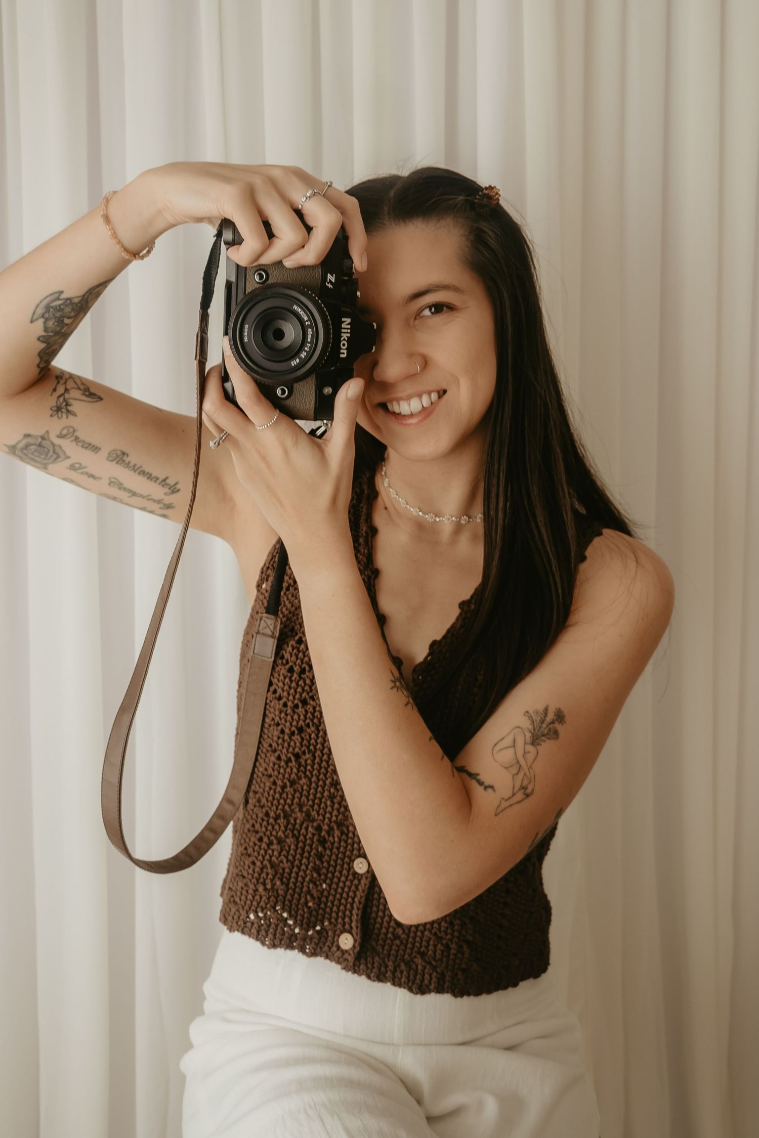 Perth newborn and maternity photographer smiling while holding a Nikon camera in her studio.