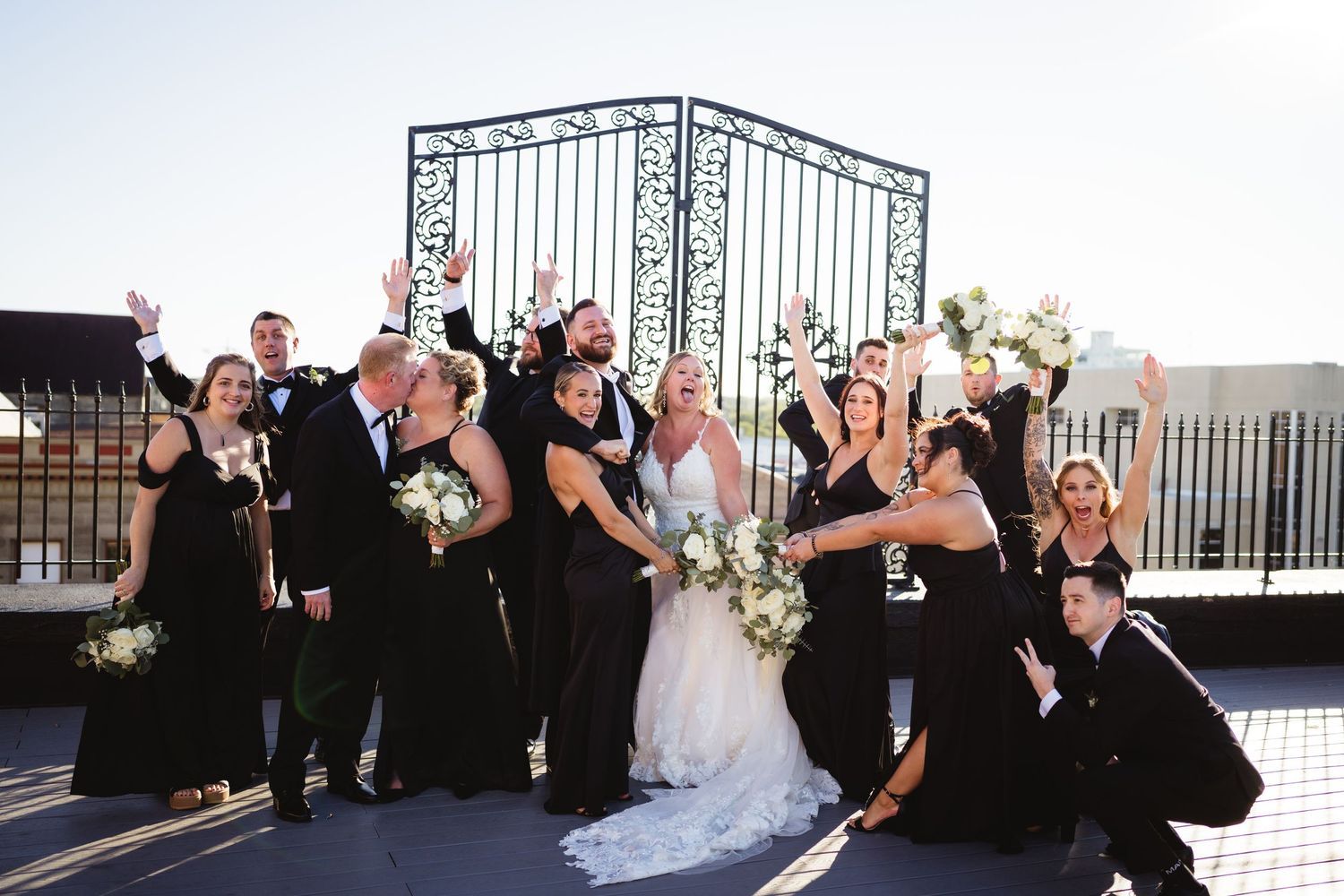 Joyful bride and groom celebrate wedding reception exit with guests holding light wands in elegant venue.