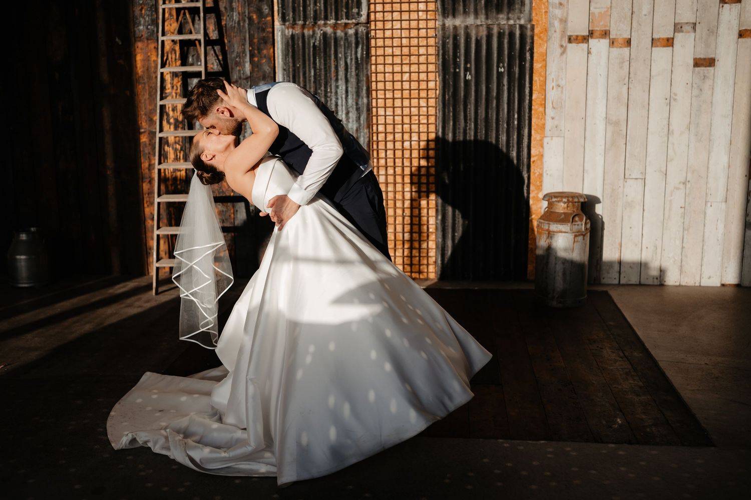 Bride and groom share a romantic dip kiss on a rooftop with the iconic Royal Liver Building in Liverpool behind them.