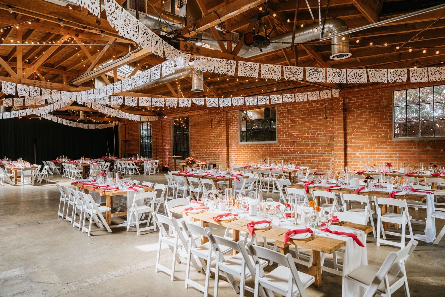 Wide view of the brick reception room with wooden tables and white chairs at Seventh Place.