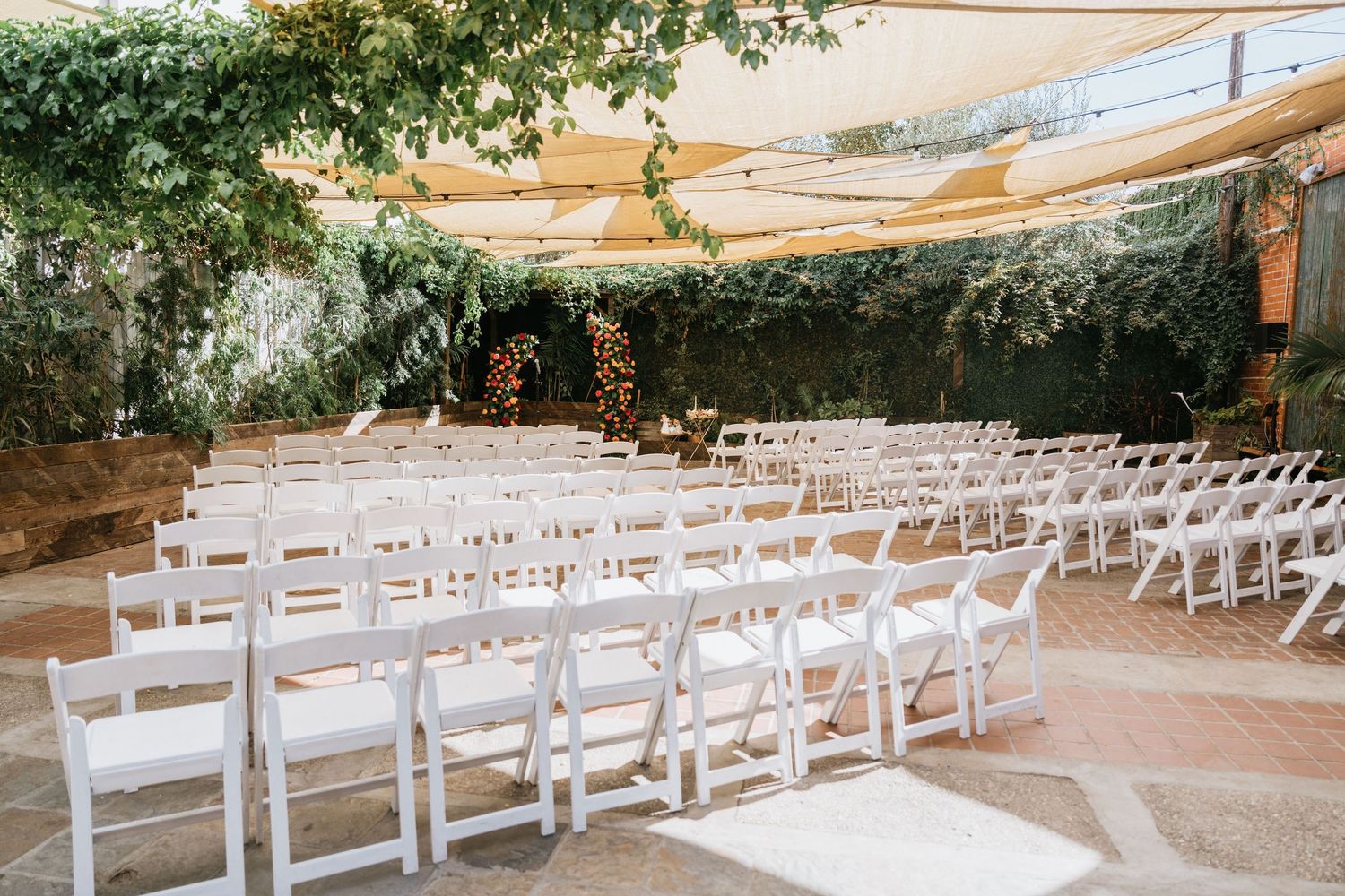 White ceremony chairs facing the colorful floral installation at Seventh Place.
