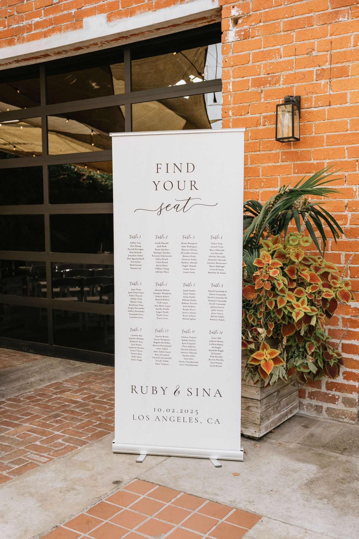 Wedding seating chart displayed on an easel at the entrance to the ceremony courtyard.