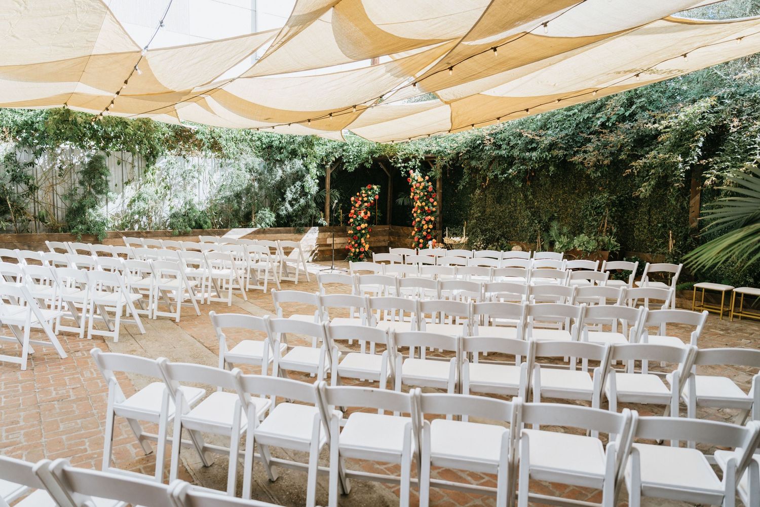Ceremony seating arranged beneath shade sails with floral ceremony arch in the background.