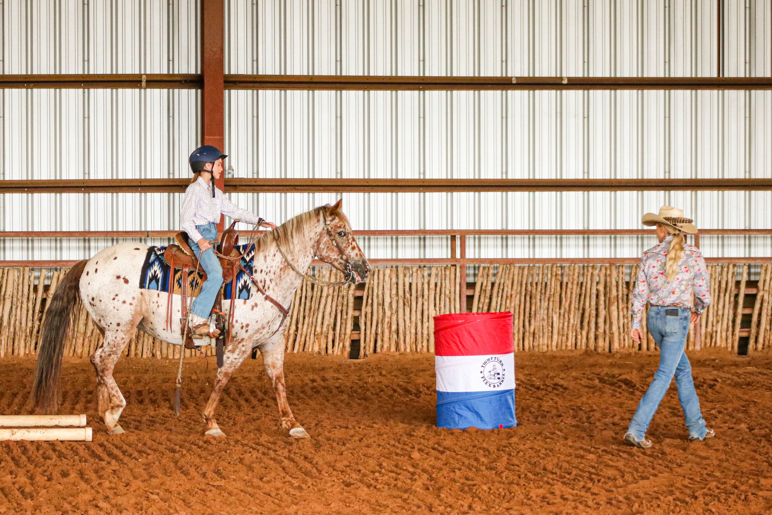 A young girl rides a pony in a western show with her mother leading the way