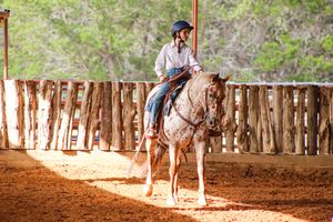 A teen girl rides a pony in a western show
