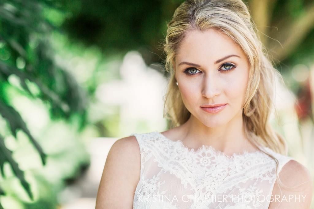 Fashion portrait in natural light against lush green foliage background.