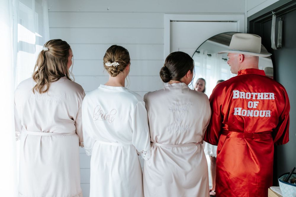 Bridesmaids in white robes with Brother of Honour in red satin robe at wedding.