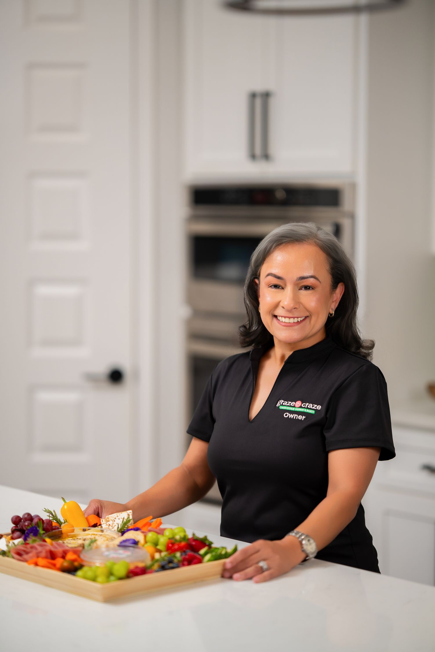 Orlando franchise branding photographer Ray Alvarez — Graze Craze Lake Nona owner in black branded uniform arranging charcuterie board