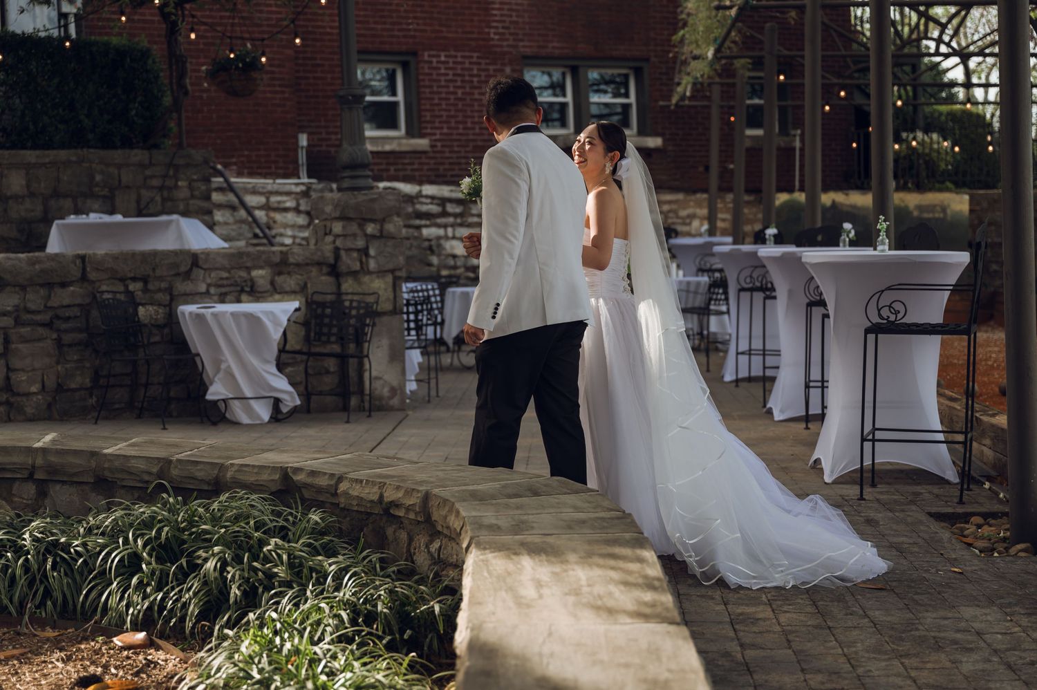 A bride and groom share a romantic first dance on an outdoor stone patio at a wedding reception venue.