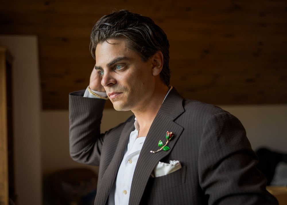 Groom in a brown pinstripe suit with boutonniere looking thoughtfully to the side.