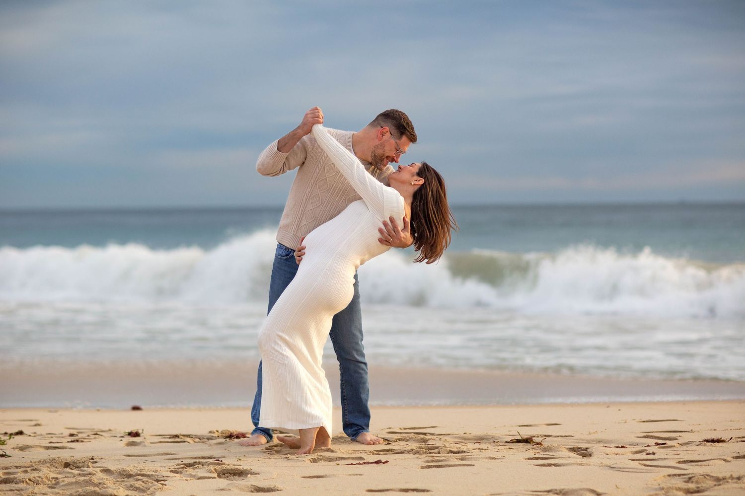 Happy couple share an intimate dance on the beach during sunset golden hour maternity photo session in perth