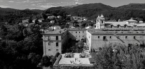 A black and white panoramic cityscape view shows historic buildings nestled among hills with mountains in the distance.