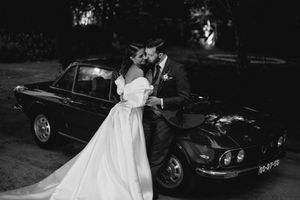A black and white wedding photo featuring a classic vintage car in the background.